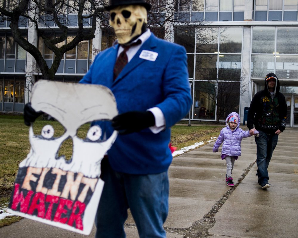 Flint resident Mike Hickey holds the hand of his daughter Natielee, 4, as they walk through pastactivists protest outside of City Hall to protest Michigan Gov. Rick Snyder's handling of the water crisis, Friday, Jan. 8, 2016 in Flint. Mich. (Jake May/The Flint Journal-MLive.com via AP) LOCAL TELEVISION OUT; LOCAL INTERNET OUT; MANDATORY CREDIT