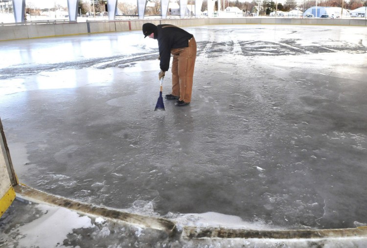 Stephen McDaniel of the Skowhegan Parks and Recreation Department on Wednesday uses a chisel too check depth of ice at public ice skating rink, which will open Thursday at the Skowhegan Fairgrounds.