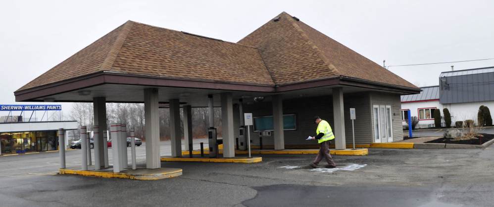 A surveyor works beside a former bank at 345 Main St. in Waterville on Monday. The city Planning Board will consider a request Monday to rezone the lot to allow a Taco Bell restaurant at the site.