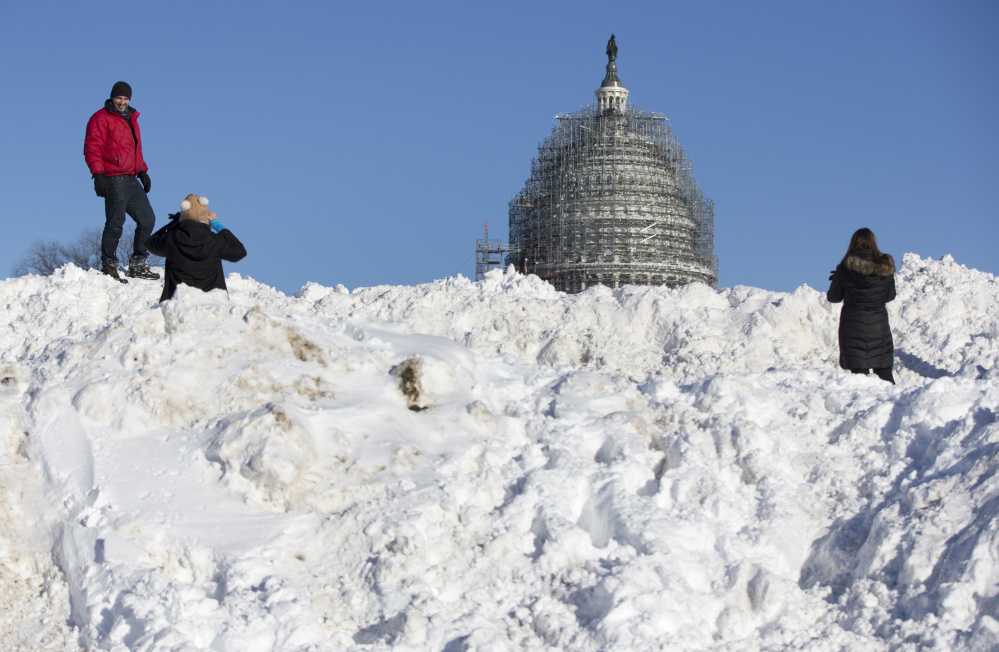 People take photographs atop a huge pile of snow in front of the U.S. Capitol in Washington on Sunday. Washington is digging out after a mammoth blizzard packed hurricane-force winds and brought record-setting snowfall.