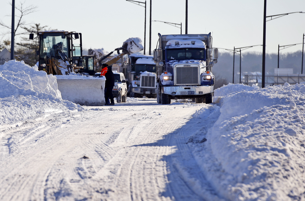 Crews work to remove the snow from a ramp for I-395 Sunday in Washington.