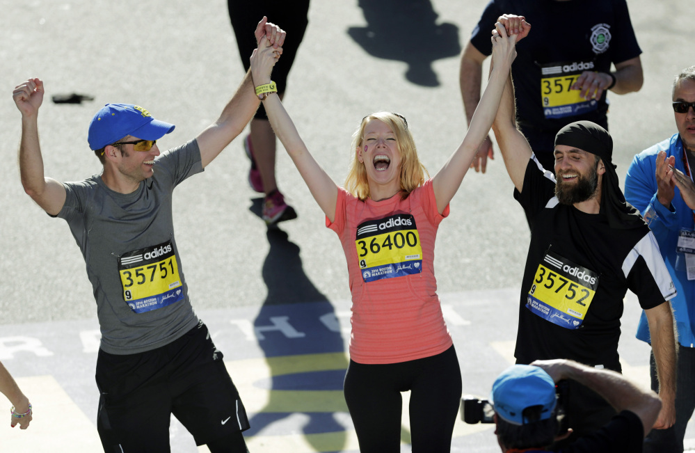 In this April 21, 2014 file photo, Timothy Haslet, left, and David Haslet, right, celebrate with their sister Adrianne Haslet-Davis at the finish line of the 118th Boston Marathon, after she completed a short distance of the course in Boston.