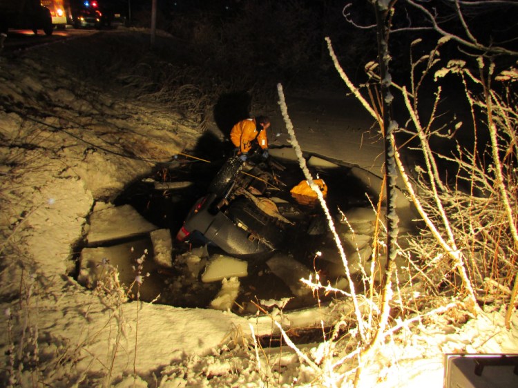 Members of the Gardiner Fire Department prepare to remove a 2003 Jeep from a pond Friday night after a crash that left a Woolwich man dead when his vehicle went off Route 27, rolled over into the pond and crashed on its roof through the ice.