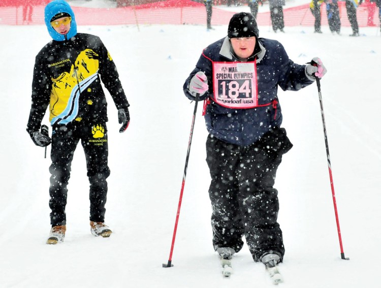 Caitlin Killarney, of Families Matter Inc., in Waterville, competes in 2014 in the 100-meter Nordic race during the 45th annual Special Olympics Maine Winter Games at Sugarloaf USA. At left, Colby Watts, of Maranacook High School cheers her on. This year’s Special Olympics begin Sunday.