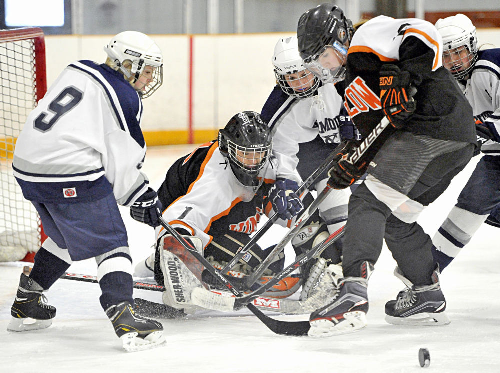 Yarmouth’s Madison McCallum, left, tries to get control of the puck in front of Winslow goalie Kiana Richards as Yarmouth’s Keely Arnold, Winslow defenseman Bailey Robbins and Yarmouth center Colleen Sullivan converge on the action during a game Saturday.