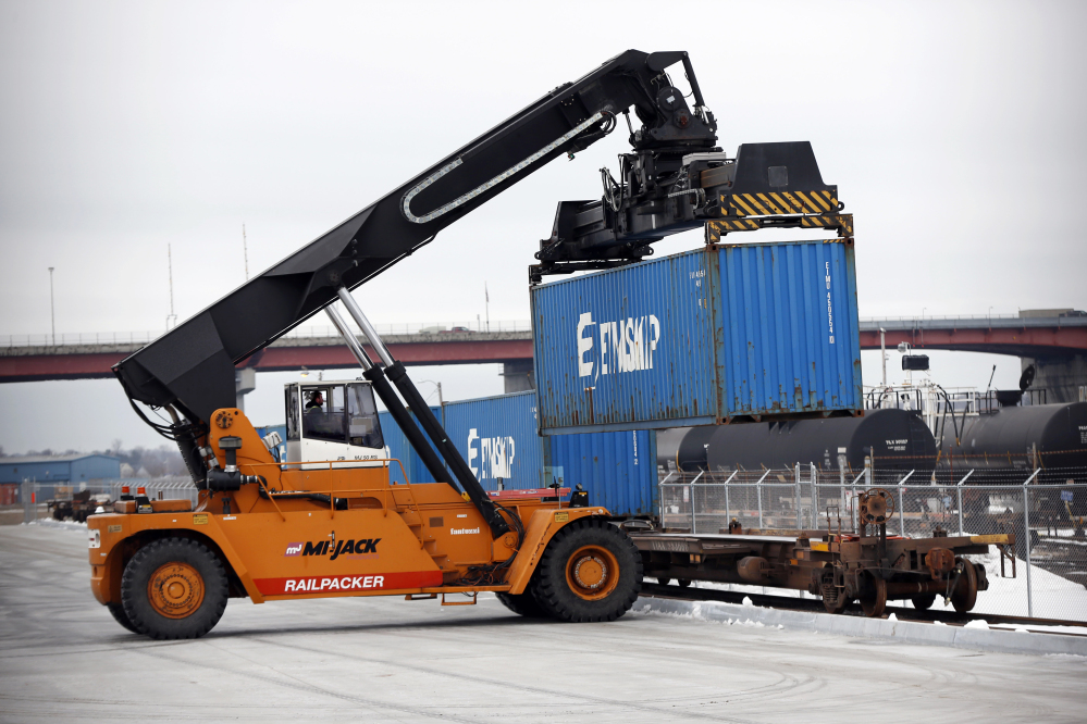 A reach stacker loads a train car with a container of Poland Spring Water on the waterfront in Portland. Freight trains are rolling through New England carrying the first-ever shipping containers loaded on the Portland waterfront.