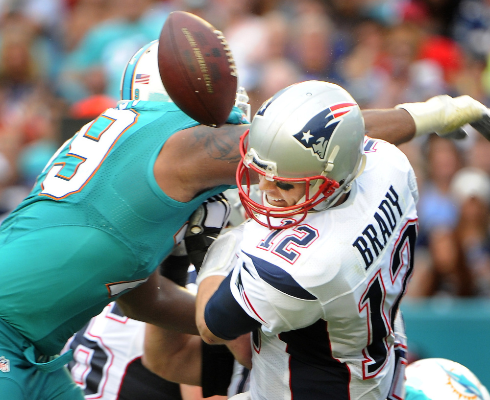 Patriots quarterback Tom Brady has the ball stripped by Miami’s Derrick Shelby during a bruising 20-10 loss to the Dolphins Sunday that denied them home-field advantage.