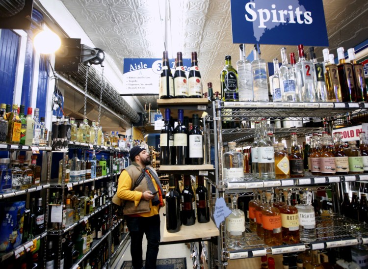 Ben Graham, 35, of Portland shops Monday at Maine Beer and Beverage Co. The new pricing system at state-run liquor stores will initially take an estimated $1.7 million from government coffers.