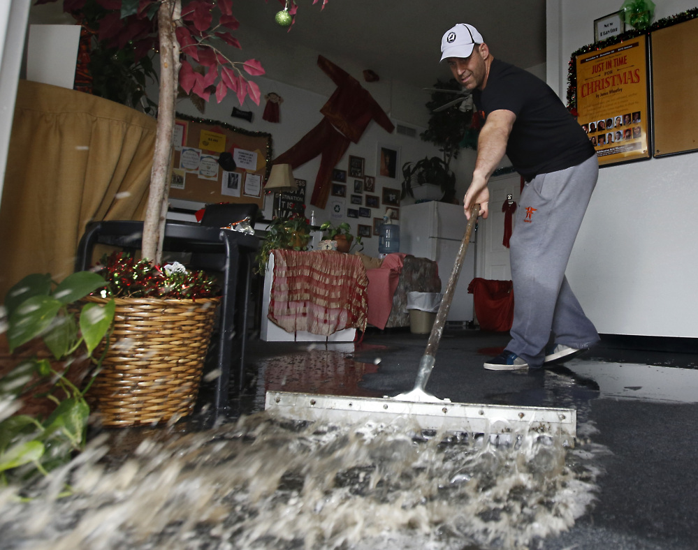 A building owner sweeps out following heavy rain in Sacramento, Calif., on Tuesday. The current El Niño has tied with the 1997-1998 one as the strongest on record.