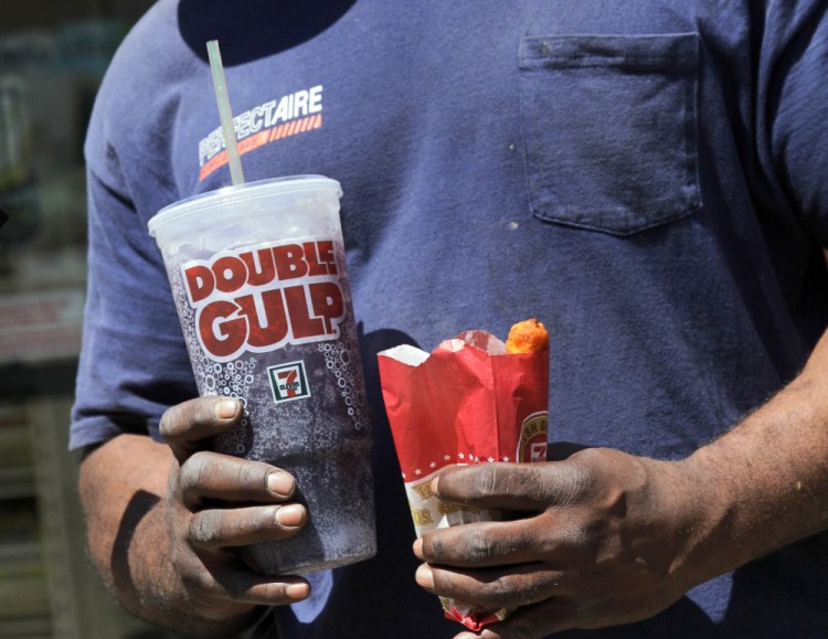 A man leaves a 7-Eleven store with a Double Gulp drink in New York. New dietary guidelines come down hard on added sugar.