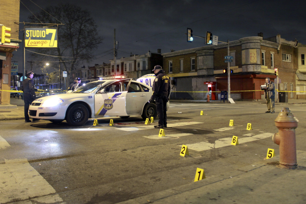 Officers investigate the scene of a shooting Friday in Philadelphia. A Philadelphia police officer was shot multiple times by a man who ambushed him as he sat in his marked police cruiser, authorities said.