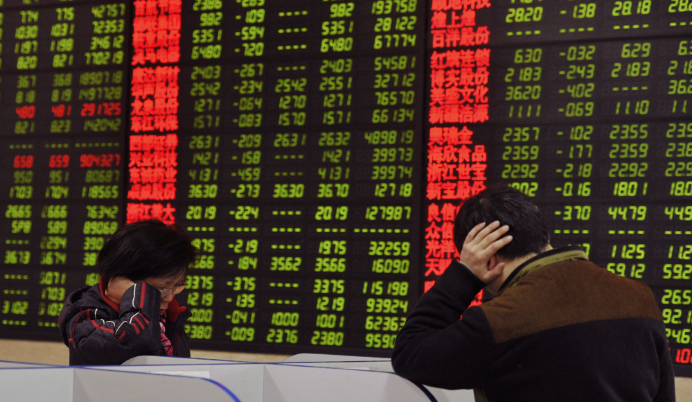 Investors check stock prices at a brokerage house in Fuyang, in China’s Anhui province, Monday. China’s stock benchmark sank more than 5 percent Monday.