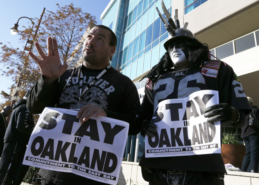 Oakland Raiders fans Griz Jones, left, and Ray Perez make their case for keeping the NFL football team in Oakland outside the Houston hotel where NFL owners were meeting Tuesday to discuss possible relocation to Los Angeles. (AP Photo/Pat Sullivan)