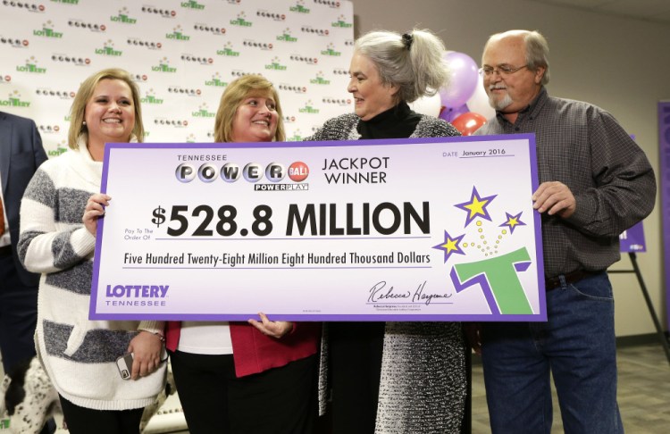 Rebecca Hargrove, second from right, president and CEO of the Tennessee Lottery, presents a ceremonial check to John Robinson, right; his wife, Lisa, second from left; and their daughter, Tiffany, left; after the Robinson’s winning Powerball ticket was authenticated at the Tennessee Lottery headquarters Friday in Nashville, Tenn.