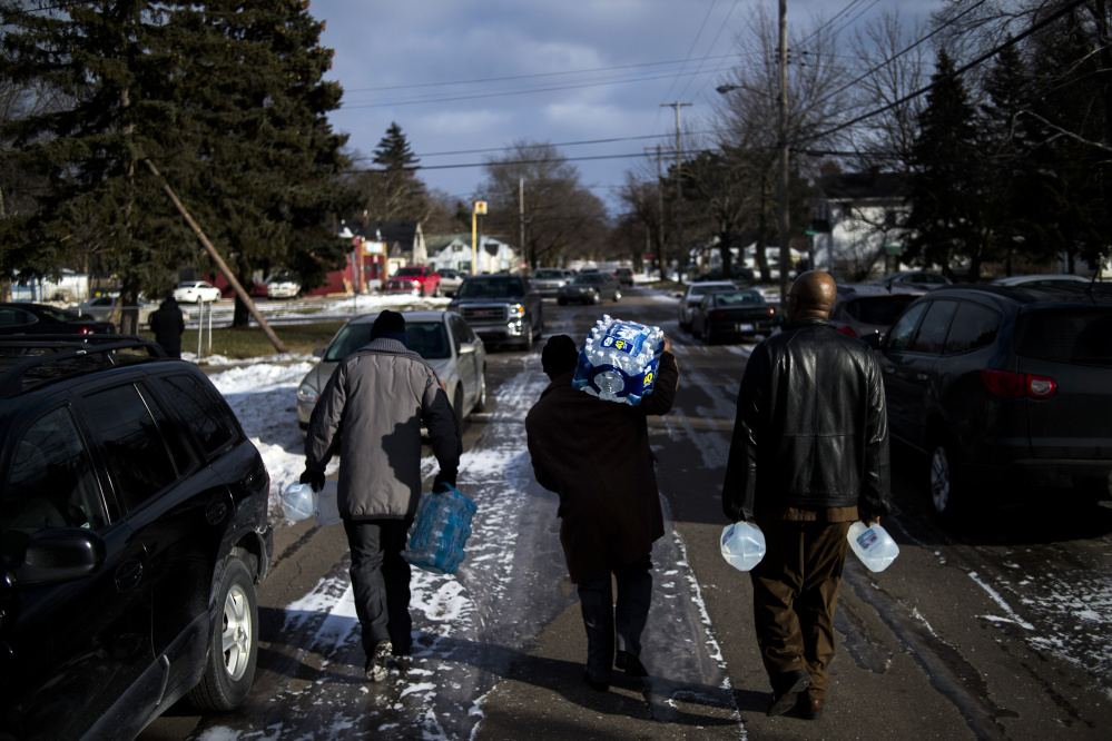 Flint residents Marcus Shelton, from left, Roland Young and Darius Martin walk on an ice-covered street as they retrieve free water Sunday at Heavenly Host Full Gospel Baptist Church in Flint, Mich. Flint’s water became contaminated after Flint switched from the Detroit water system to the Flint River as a cost-cutting move.
