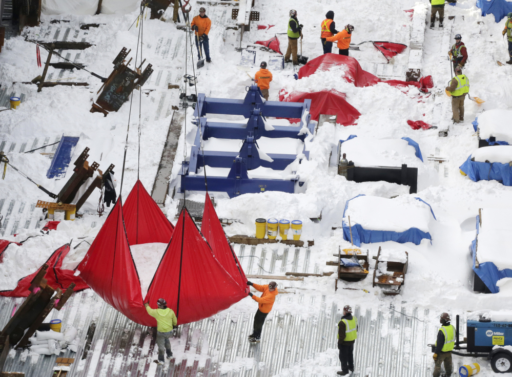 A crane hoists a large red tarp filled with snow Monday from a construction site at Hudson Yards in New York City. City officials sent out 4,600 workers and more than 2,000 pieces of equipment to clear the 27 inches of snow that fell during a blizzard Friday and Saturday.
