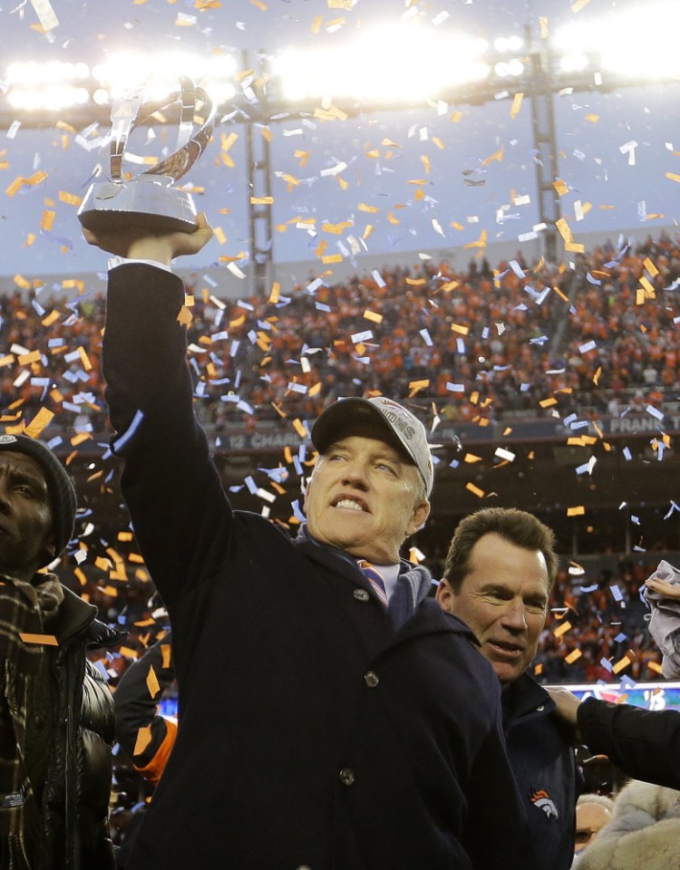 Denver Broncos general manager and executive vice president of football operations John Elway raises the AFC trophy following the AFC championship game.