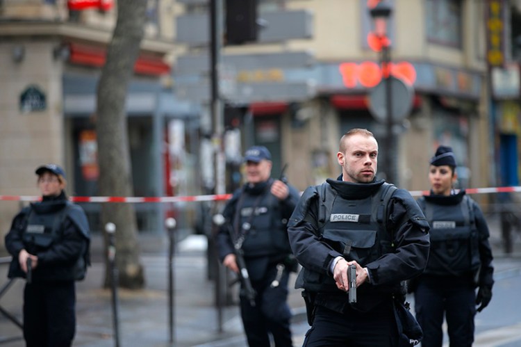 Police officers secure the perimeter near the scene of a fatal shooting which took place at a police station in Paris on  Wednesday. Two officials say the man had wires extending from his clothing and a knife.