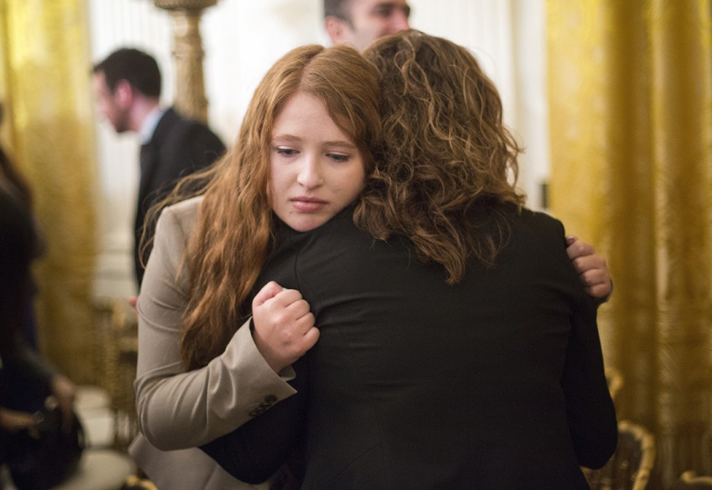 White House guests and victims of gun violence console one another after listening to President Barack Obama speak in the East Room Tuesday about steps his administration is taking to reduce gun violence. The Associated Press