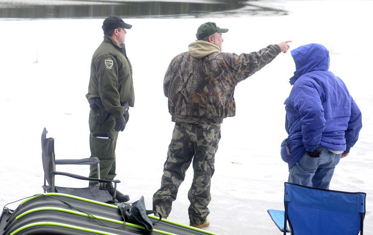 Game Warden Steve Allarie, left, checks ice fishermen Dennis Simard, center, and Marcel Chrissman on Lower Narrows Pond in Winthrop on Monday. With traps a few yards from open water, Allarie urged the anglers to exercise caution on the unseasonably thin ice.