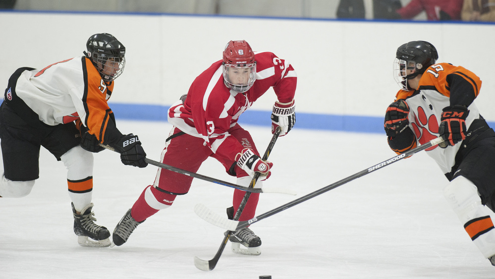 Cony forward Connor Perry, center, brings the puck down the ice during a game against Gardiner earlier this season at the Ice Vault in Hallowell.