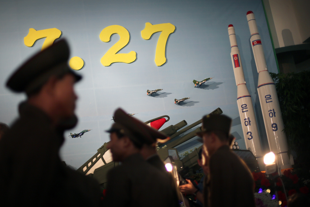 In this July 26, 2013, photo, North Korean soldiers are silhouetted against model versions of the Unha 3 space launch vehicle which successfully delivered North Korea’s first satellite into Earth orbit, and the Unha 9, right, which would carry a lunar orbiter, on display at an annual flower show held in honor of national founder Kim Il Sung and his son Kim Jong Il, in Pyongyang, North Korea.