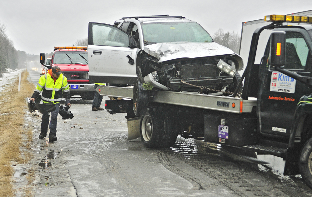 A tow truck driver carries broken vehicle pieces to throw onto the flatbed with a wrecked Saturn Vue around 1:45 p.m. Wednesday along northbound lanes of Interstate 95 near the Town Farm Road overpass in Sidney. The accident was among several Wednesday following periods of freezing rain. 