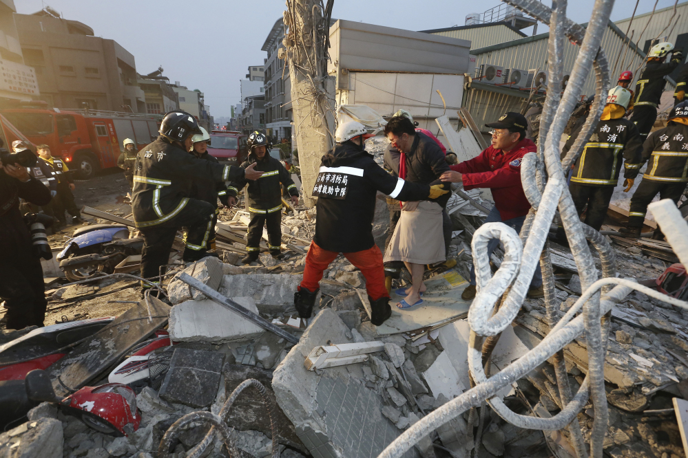 Rescue workers guide a man from the rubble of a toppled building after an earthquake in Tainan, Taiwan, Saturday.