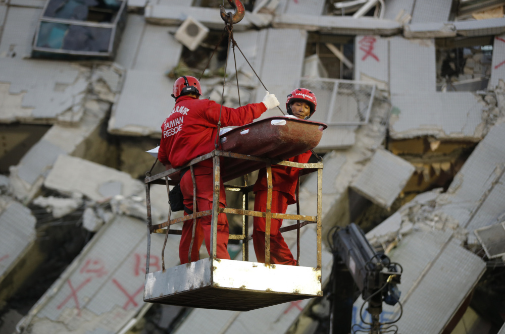 Emergency workers carry a victim recovered from a collapsed building in Tainan, Taiwan, on Sunday. Rescuers found more signs of life in the wreckage of a high-rise apartment building that collapsed in a powerful earthquake in southern Taiwan.