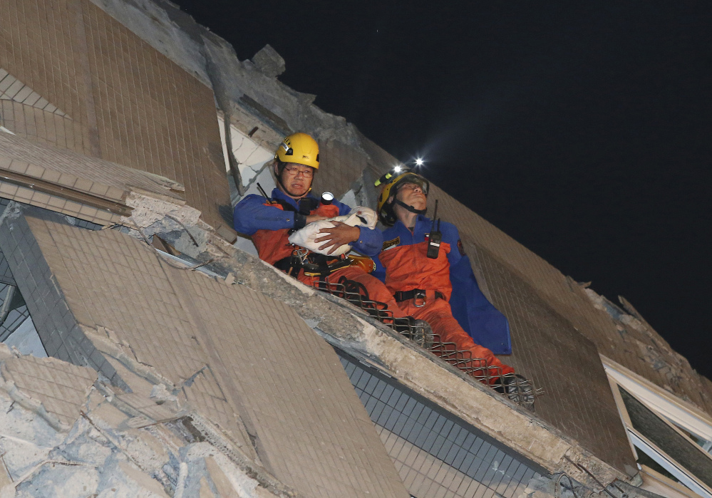 Rescue workers carry a baby swaddled in a cloth from the rubble of a toppled building after an earthquake in Tainan, Taiwan, Saturday.