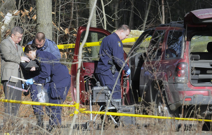 Maine State Police detectives examine the SUV containing the bodies of Eric Williams and Bonnie Royer, who were found dead on Sanford Road in Manchester early Christmas morning.