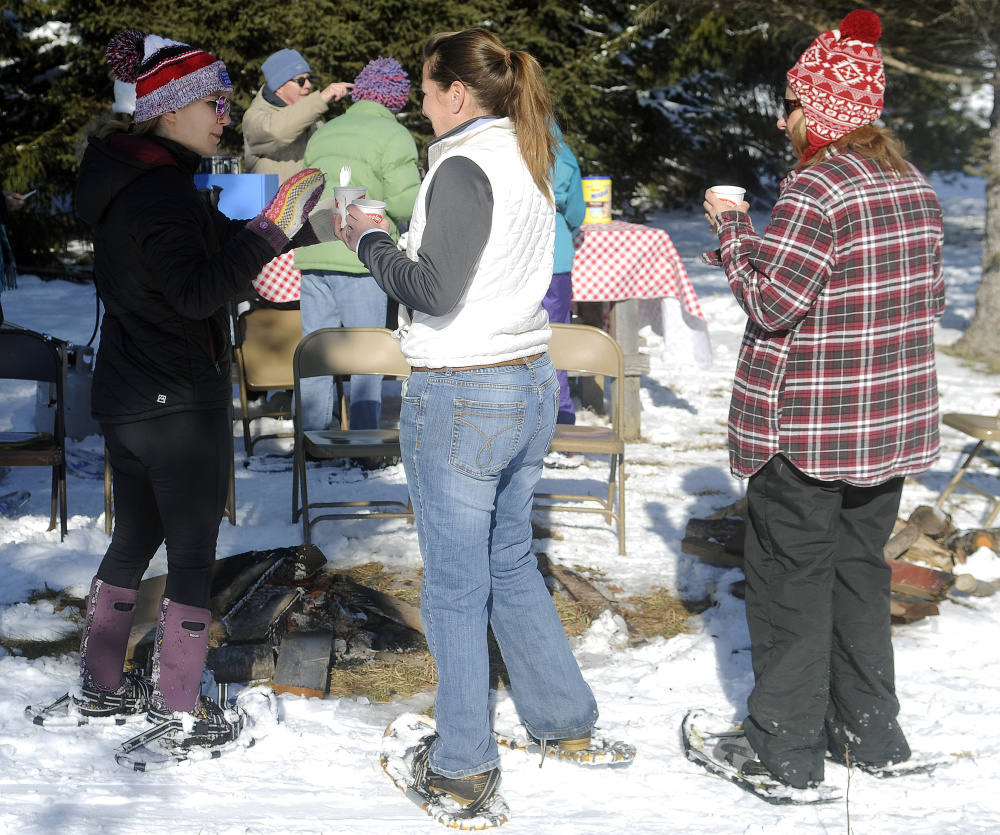 People warm up Sunday next to a fire at Viles Arboretum in Augusta during the Table Tour fundraiser.