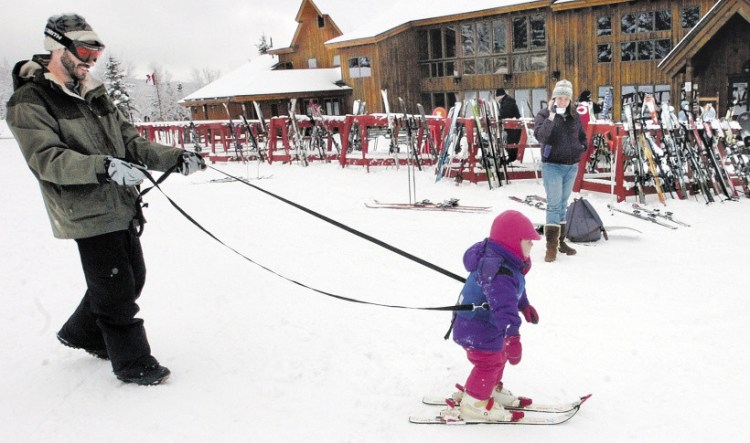 A child is held by a tether line by her father while skiing for the first time near the base lodge at Saddleback ski resort near Rangeley in March 2009 . Owners say the resort will not open in time for the February school vacations later this month.