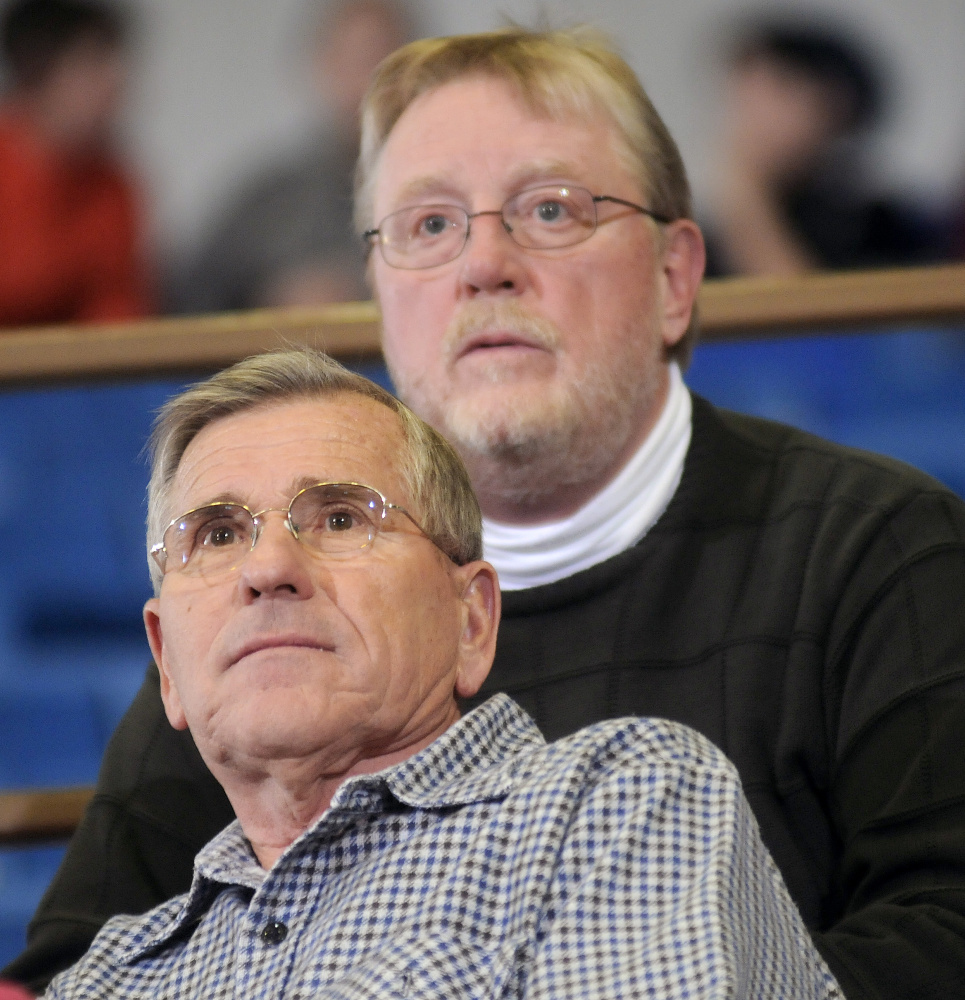 Mark Damren, back, and Ronald Emmons watch the Class AA North boys quarterfinal game between Edward Little and Cheverus on Thursday night at the Augista Civic Center. Damren has sat in the same seat for tournament games at the Civic Center since 2007.