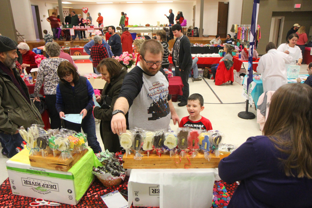 Cody Dow, of Benton, helps his 6-year-old son, Max, pick out a treat from Terry Fouquette’s offerings Saturday at the annual Fairfield Chocolate Festival. Fouquette owns Terry’s Country Candies, of New Gloucester. The event, held in the Fairfield Community Center, raised money for the Fairfield Council of Churches Emergency Heating Fund.