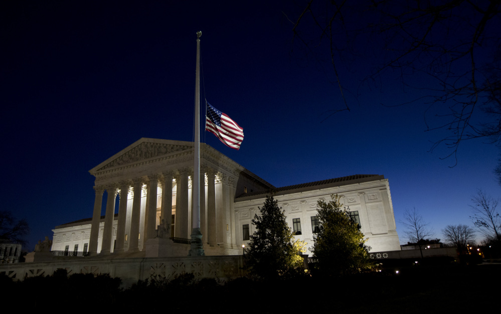 An American flag flies at half-staff in front of the U.S. Supreme Court building in honor of Supreme Court Justice Antonin Scalia as the sun rises in Washington, Sunday.