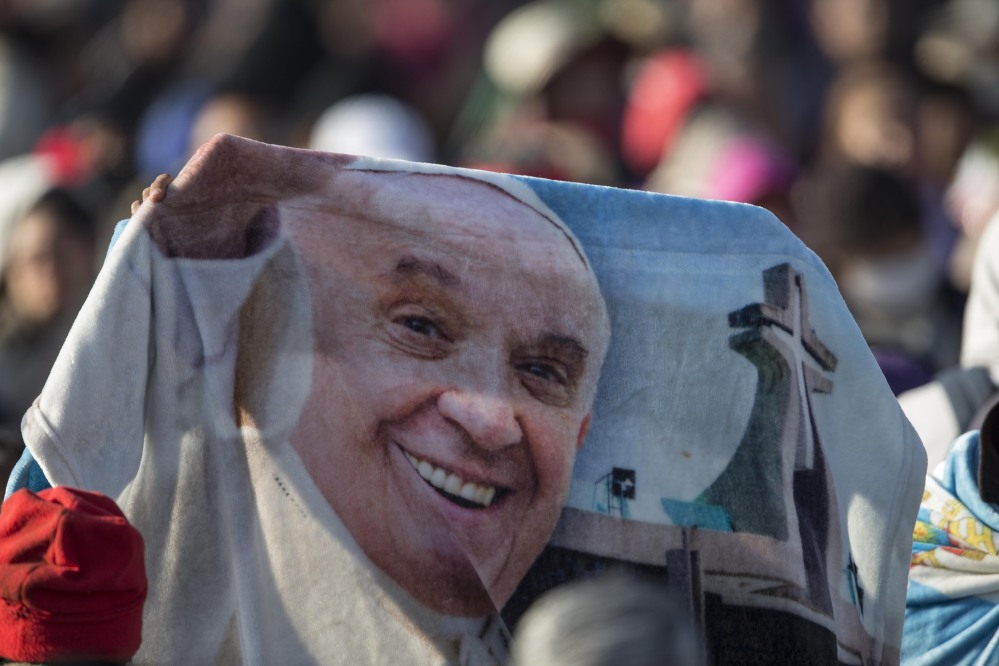 A person holds a blanket with the image of Pope Francis during the wait for the arrival of the Pope to Ecatepec, Mexico, Sunday.