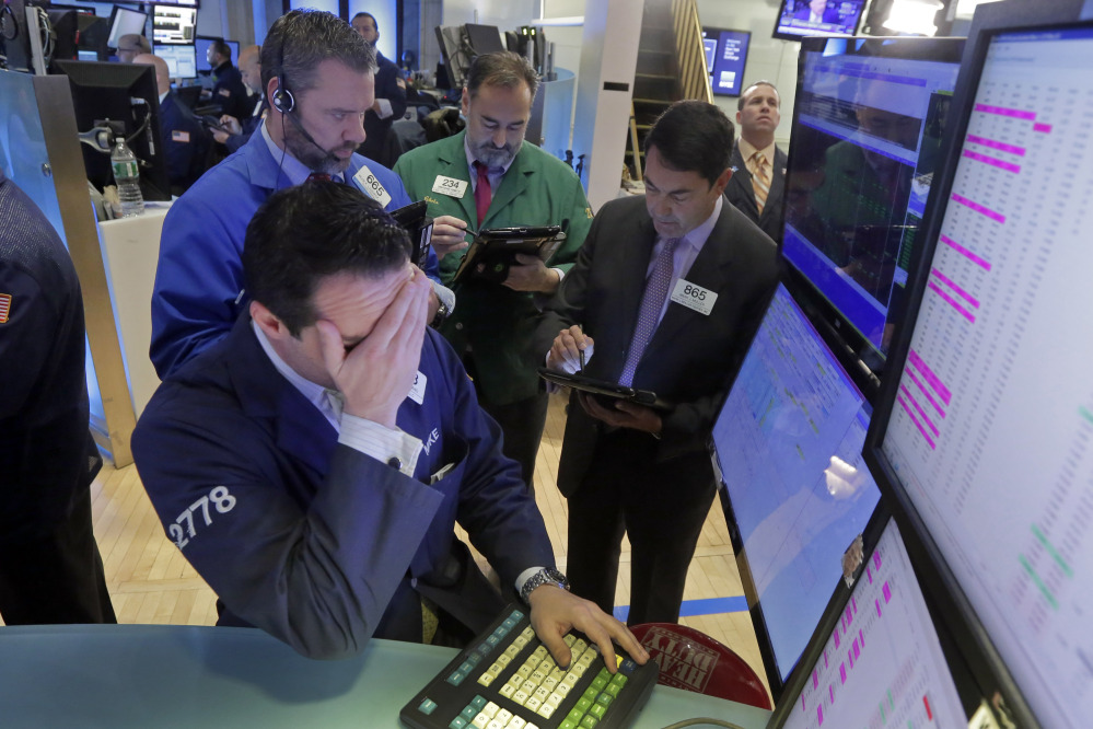 In this Feb. 1, 2016, file photo, specialist Michael Gagliano, foreground, works with traders at his post on the floor of the New York Stock Exchange.