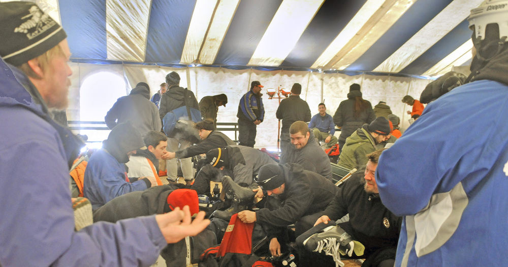 Players warm up and change Sunday under a tent during the Maine Pond Hockey Classic at the Snow Pond Center for the Arts in Sidney.