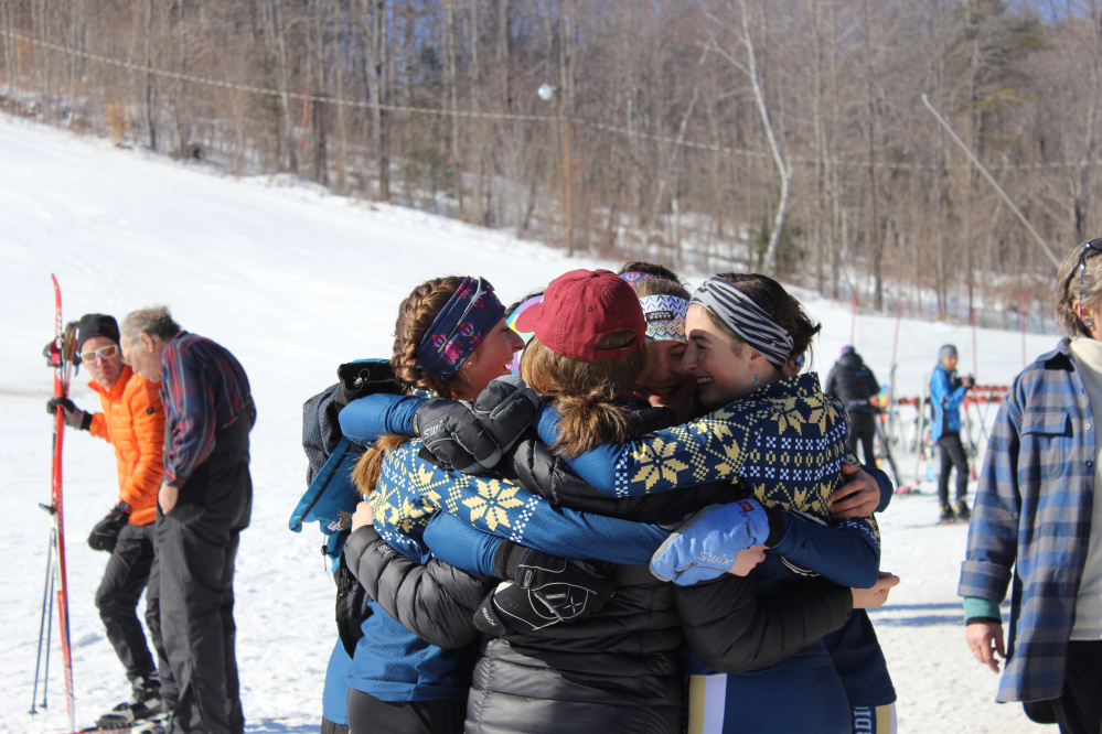 Mt. Blue Nordic skiers, from left, Zoe Huish (with braids), Julia Ramsey, Kayla White and River Lisius hug after the Cougars won the Class A Nordic state title Friday at Titcomb Mountain.