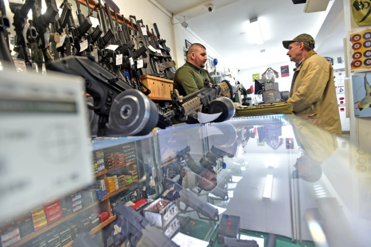 Amos Herrera, left, helps Neil Wooley, right, of Vassalboro, purchase a hand gun at Fox’s Firearms Sales & Training Service in Vassalboro on Friday.