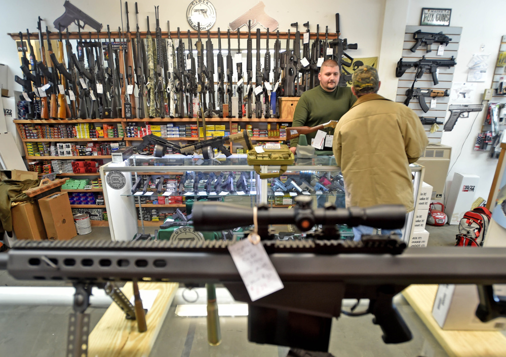 Amos Herrera, facing, helps Neil Wooley, right, of Vassalboro, purchase a hand gun at Fox’s Firearms Sales & Training Service in Vassalboro on Friday.