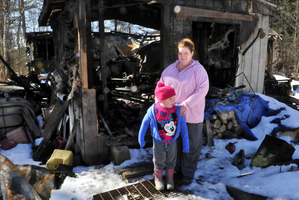 Tornia Bowring and her granddaughter, Serenity, on Monday, stand outside the Norridgewock home they and her husband Maurice lived in when it was destroyed by fire last month. The family and friends say someone has taken items donated by area stores for a March benefit for the family.