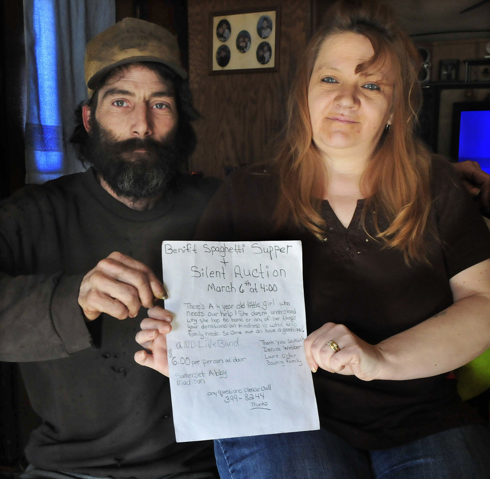 Bill Allen and Denise Webber on Monday hold a sign that was posted in Norridgewock area stores promoting a supper benefit for fire victims Maurice and Tornia Bowring. Similar signs have been taken from area stores.