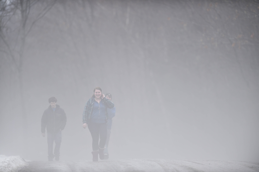 Ashlyn Laliberte, of Canaan, and Gilly Barrows, left, emerge from the fog as they walk along Quarry Road in Waterville on Thursday.