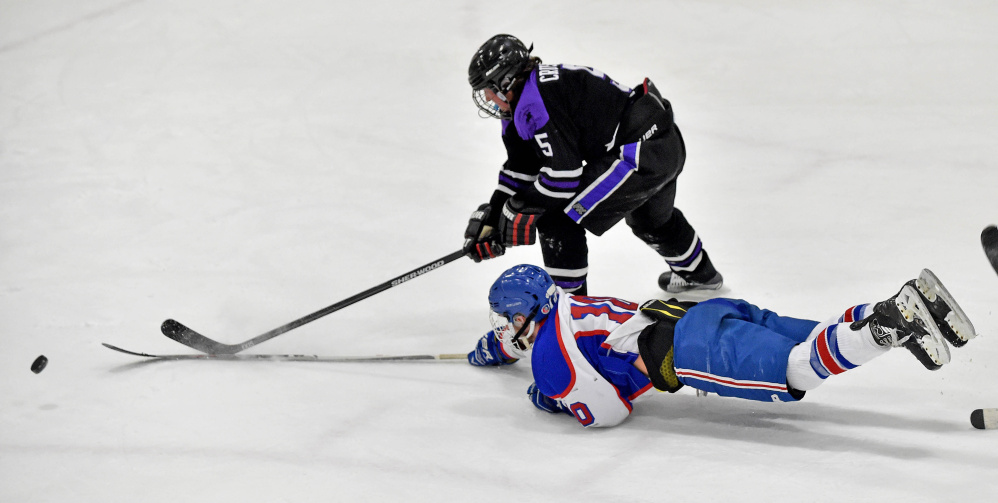 Messalonskee forward Brandon Nale (10) dives to the puck as John Bapst’s Tyler Wheeler closes in during the third period of a Class B North quarterfinal Tuesday night at Sukee Arena.