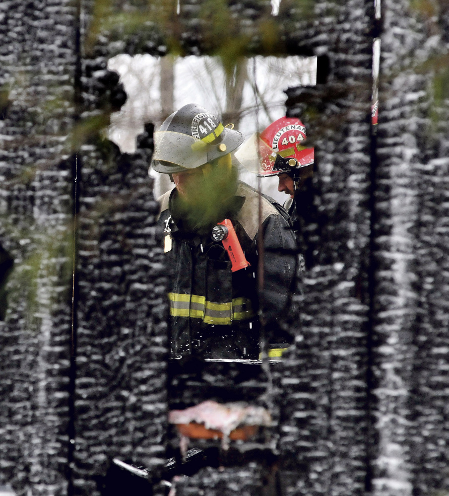 Firefighters can be seen through two burned out walls of a garage that was destroyed by fire on the Huff Hill Road in Hartland on Sunday.