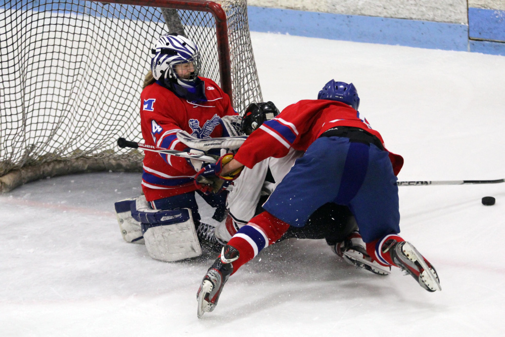 Messalonskee freshman goalie Amber Kochaver holds her ground as teammate Dylan Burton falls on a Camden Hills player in front of the net during a Class B North semifinal Saturday at Sukee Arena.