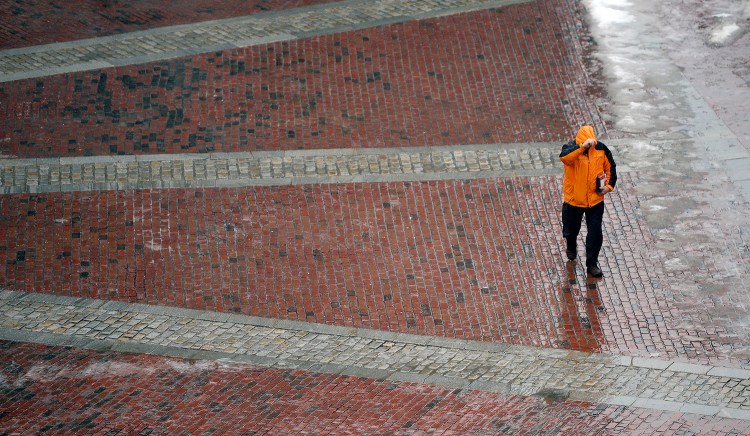 A pedestrian holds his hood in place as the wind blows while he walks through Monument Square in Portland Tuesday. Shawn Patrick Ouellette/Staff Photographer