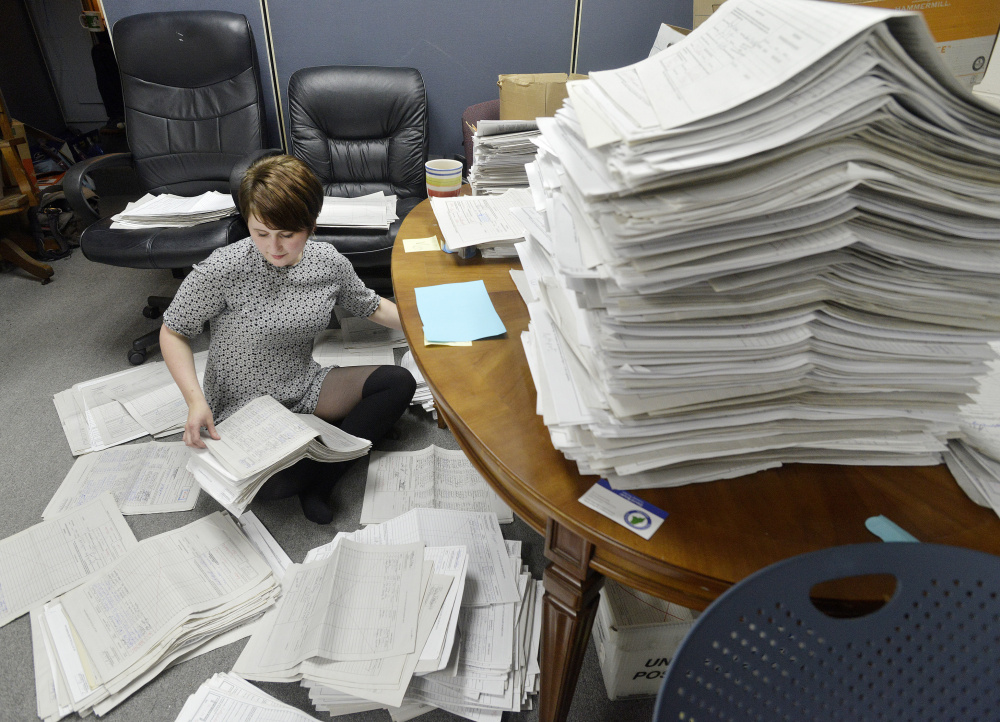 Allison Cormier, a volunteer for the marijuana legalization campaign, sorts petitions at the office in Falmouth. 
John Ewing/Staff Photographer